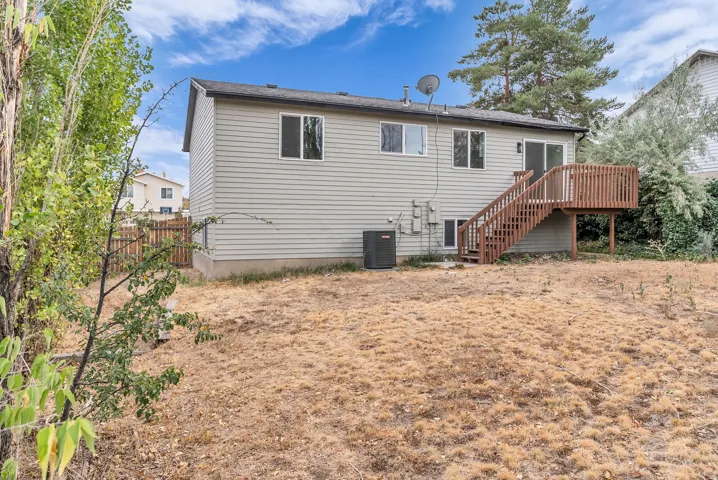 Exterior featuring siding, multiple windows, and a wood-finish deck with stairs