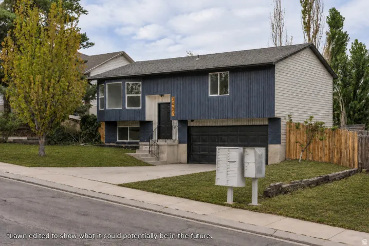 Split-level residence featuring vertical and horizontal siding, an attached garage, a concrete driveway, and a wood privacy fence