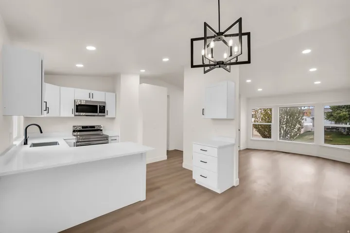 Contemporary kitchen with white cabinetry, stainless steel appliances, a black matte faucet, and wood-finish flooring