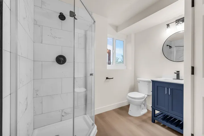 Glass-enclosed shower with subway tile surround and dark bronze fixtures