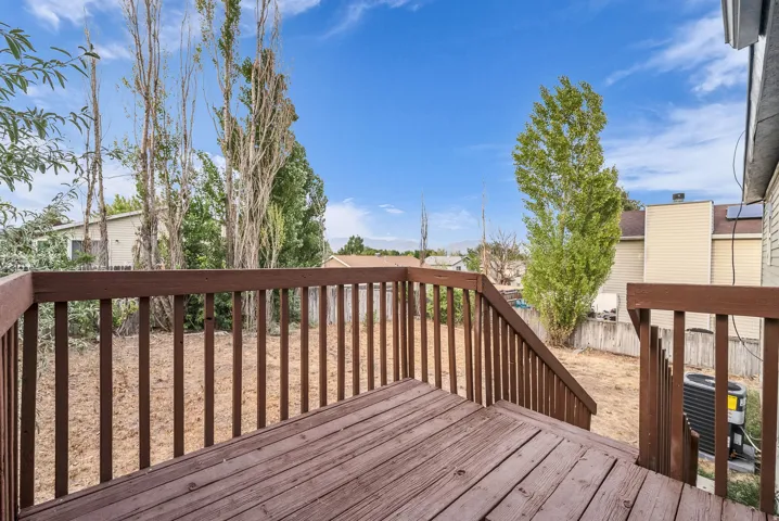 Spacious composite deck featuring horizontal wood-finish railings, multiple levels, and mature landscaping with tall poplar trees