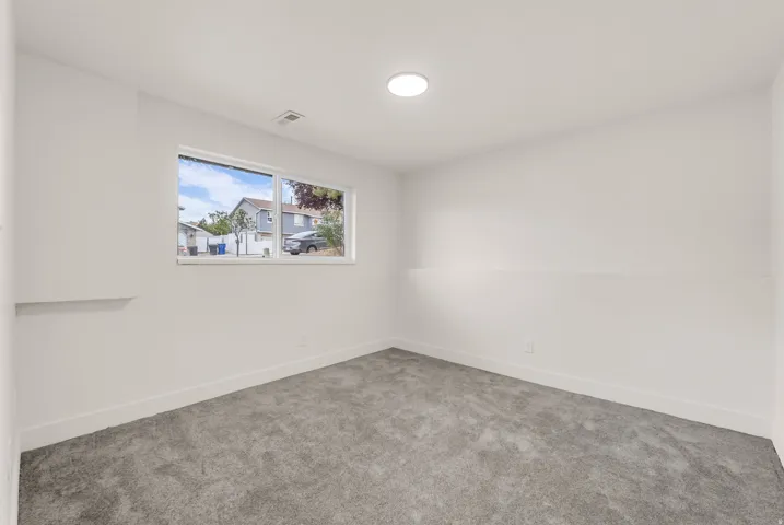 Recessed ceiling lighting, a large window, and gray carpet flooring