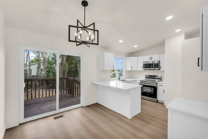 Modern kitchen with white cabinetry, stainless steel appliances, light-toned countertops, and wood-finish flooring