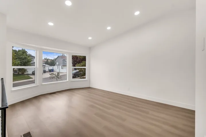 Wood-finish flooring, recessed lighting, and a curved bay window