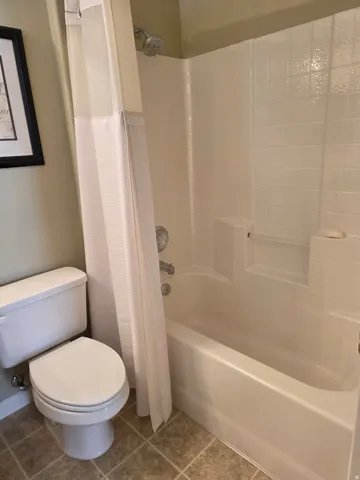 Full-size bathtub with integrated shower, white tile surround, and chrome fixtures