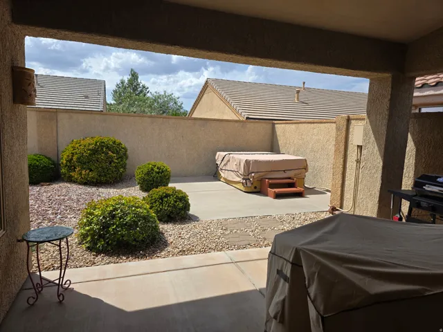 Covered patio with integrated wall sconce lighting, concrete flooring, and an enclosed backyard