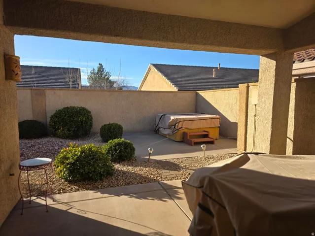 Covered patio area with concrete flooring, gravel landscaping, and established shrubbery
