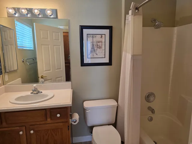 2nd Bathroom featuring a single vanity with wood-finish cabinetry, a white countertop with an integrated sink, and a shower-over-tub combination with a tiled surround