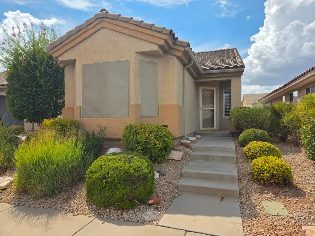 Stucco exterior with a tile roof, covered entry, and a concrete pathway