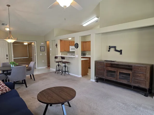 Vaulted ceilings, carpeted flooring, kitchen pass-through with breakfast bar, ceiling fan, and recessed lighting