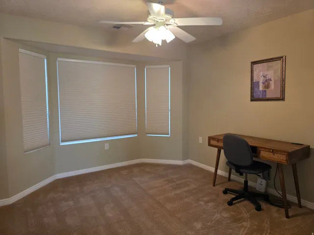 2nd Bedroom/Office with Bay window with custom cellular shades, ceiling fan with integrated lighting, and neutral wall tones