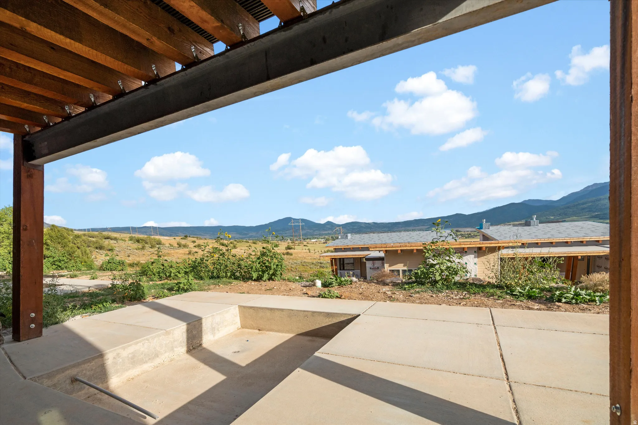 Outdoor living area with concrete patio, built-in concrete seating, and a wood and metal pergola structure