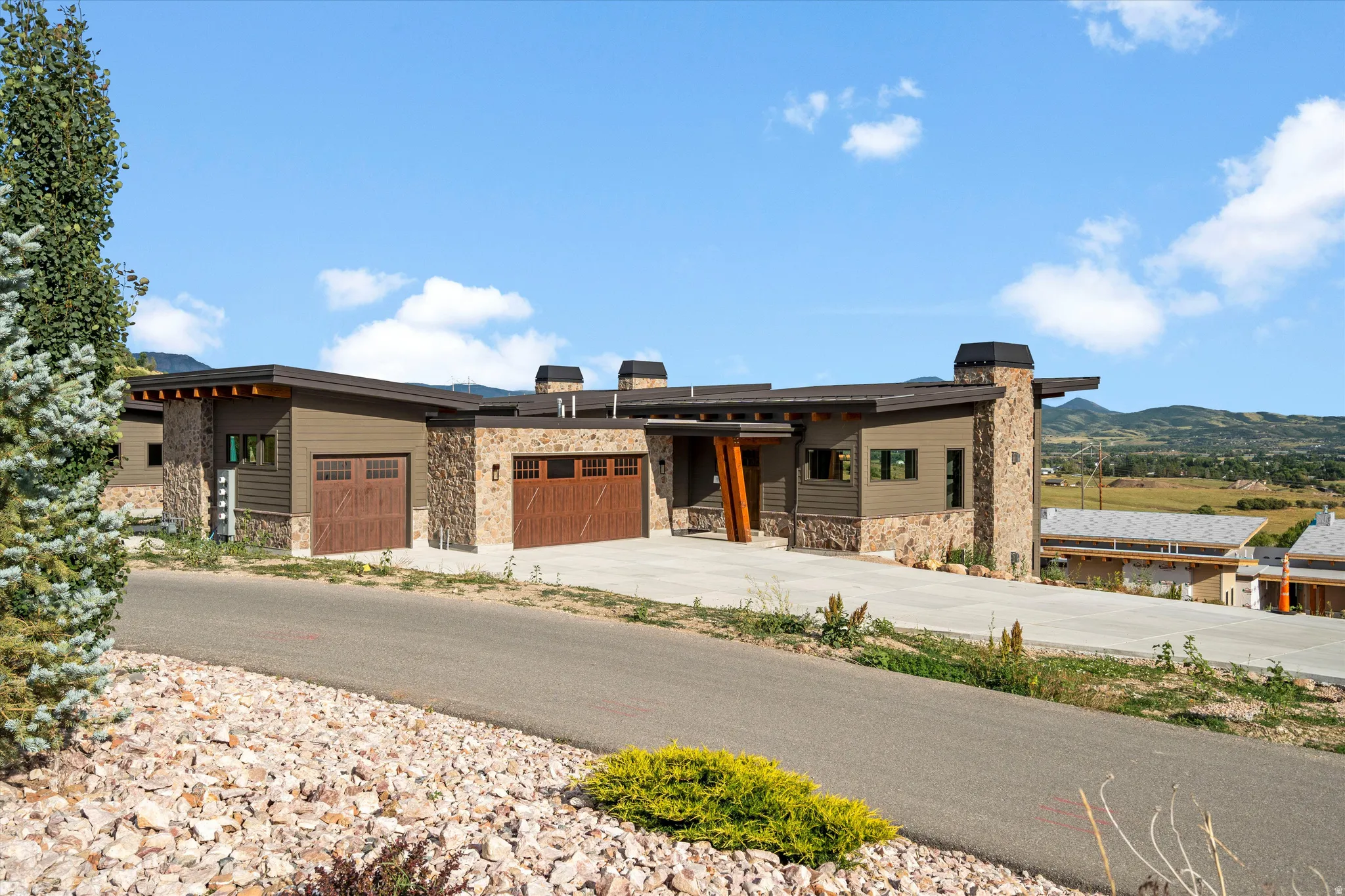 Contemporary exterior featuring stone accents and wood-finish garage doors
