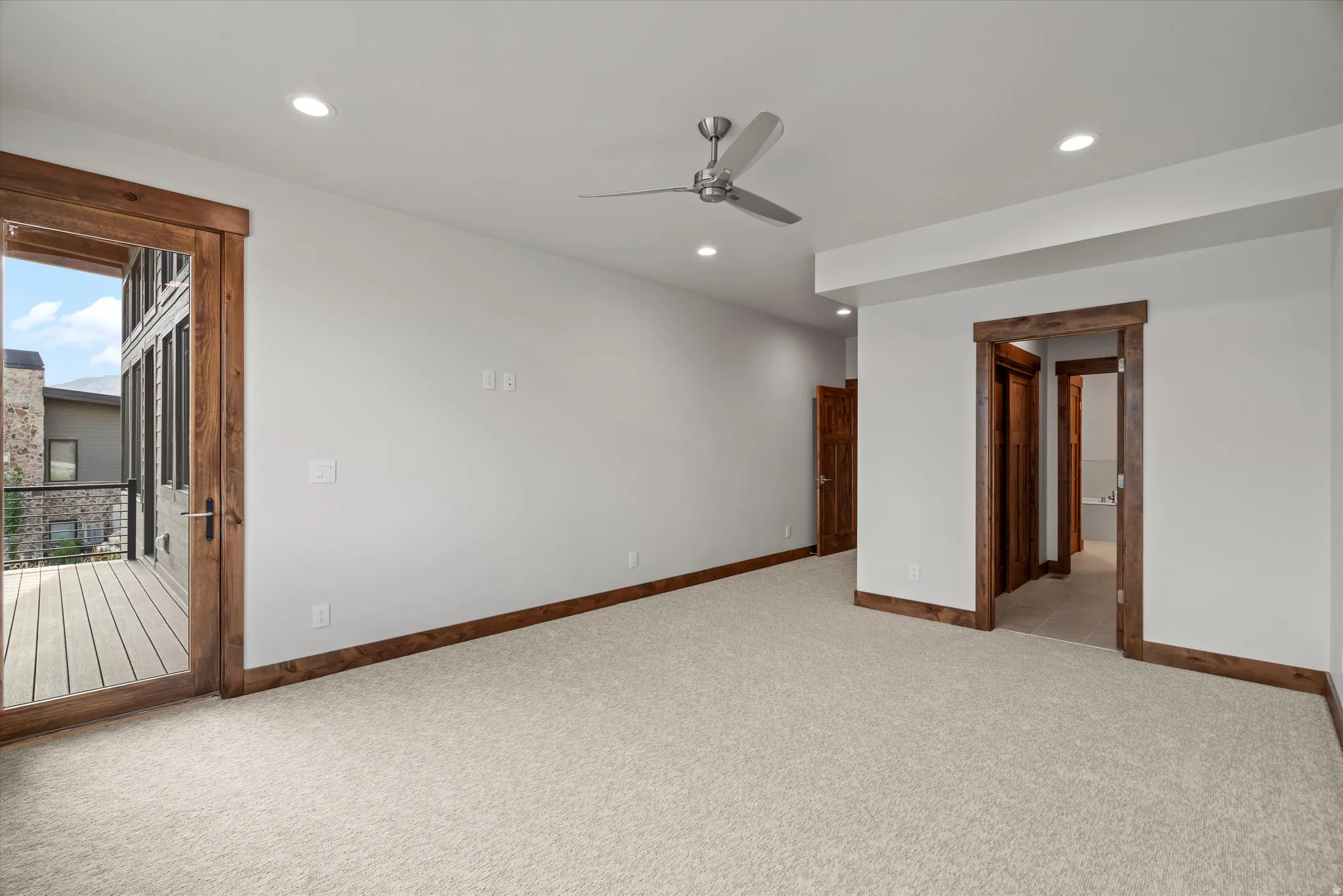 Recessed lighting, ceiling fan, wood-frame door to exterior balcony, wood-frame interior doorway, and neutral carpet flooring