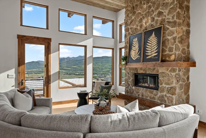 Stone fireplace with a wood mantel, wood-framed windows, and a wood-beamed ceiling