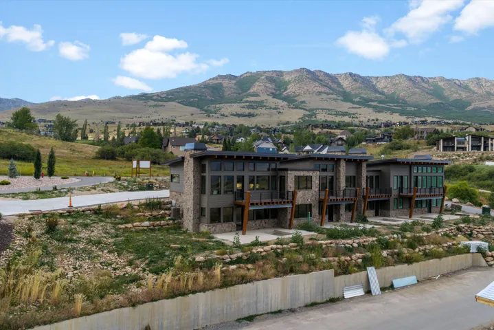 Contemporary architecture featuring multi-story design, expansive windows, multiple balconies, and stone and siding exterior finishes