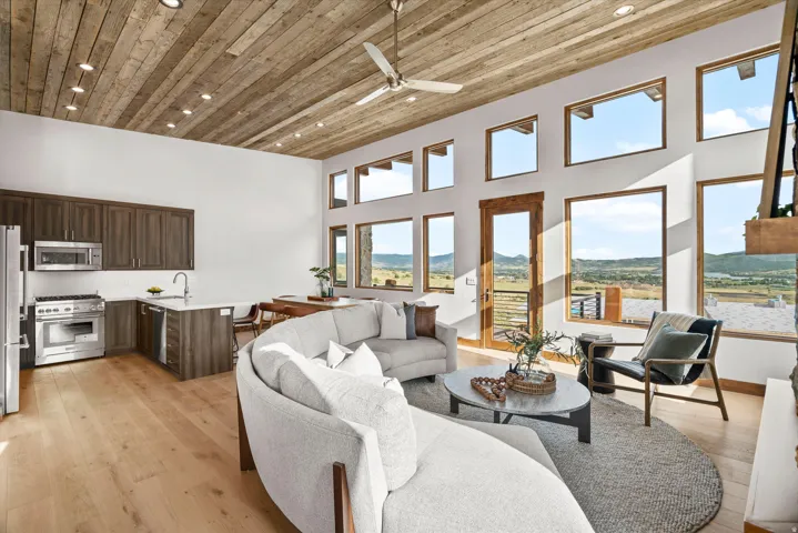 Vaulted wood-plank ceiling with recessed lighting, full-light entry door, hardwood flooring, and stainless steel appliances