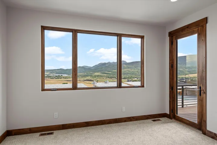 Expansive window with mountain scenery, rich wood-finish trim, glass-paneled door, and plush carpet flooring
