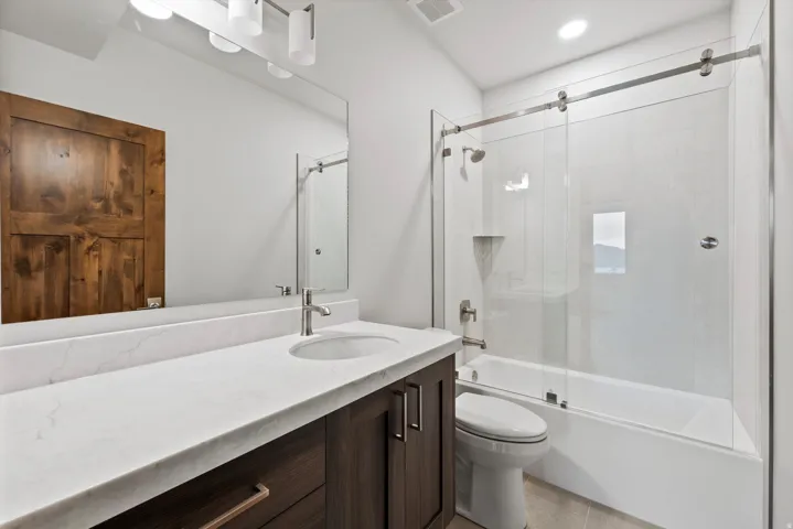 White countertop with an undermount sink, dark wood-finish vanity, and a large mirror