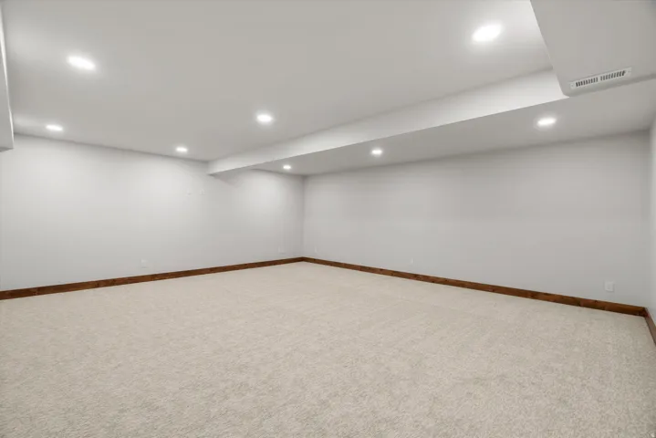 Recessed ceiling lighting, light-toned wall paint, neutral carpeting, and wood-finish trim