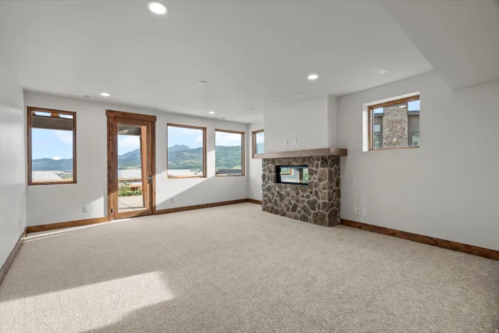 Bright, open living space flooded with natural light through expansive multi-pane glass doors and windows framing scenic water and mountain vistas
