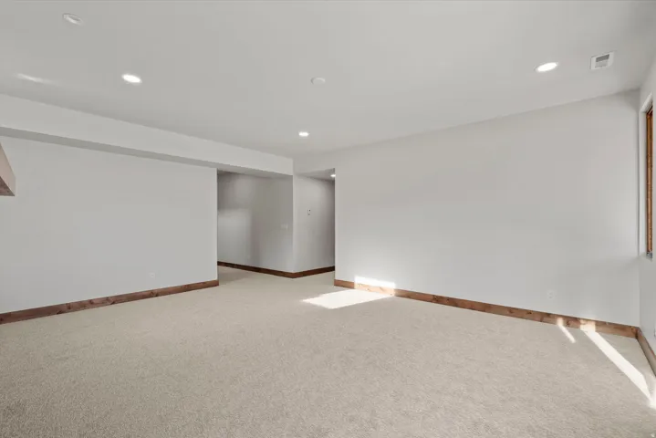 Recessed lighting illuminates neutral carpeting and light-toned walls with wood-finish trim