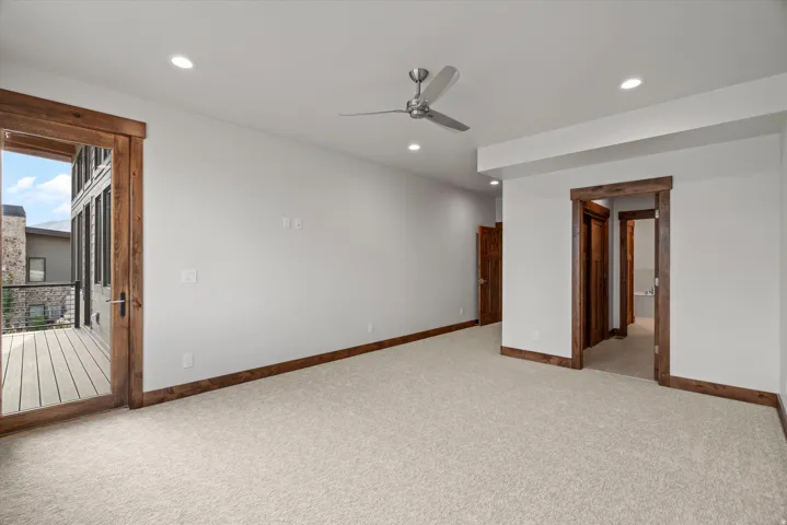 Recessed lighting, ceiling fan, wood-frame door to exterior balcony, wood-frame interior doorway, and neutral carpet flooring