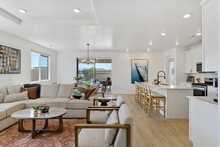 Open-concept living space with wood-finish flooring, recessed lighting, and a tray ceiling