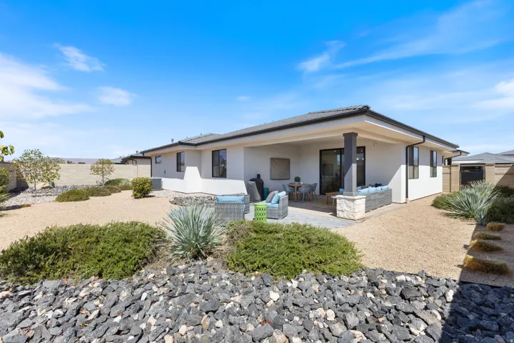 Exterior featuring a covered patio, stucco siding, a tiled roof, and drought-tolerant landscaping with gravel and natural rock elements
