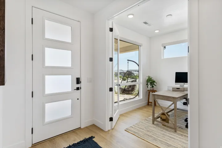 Frosted glass entry door with matte black hardware, wood-finish flooring, recessed lighting, and a dedicated room with a large window