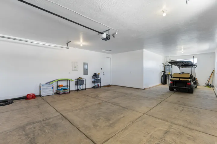 Spacious garage featuring a concrete floor, white walls, overhead lighting, and an automatic garage door opener