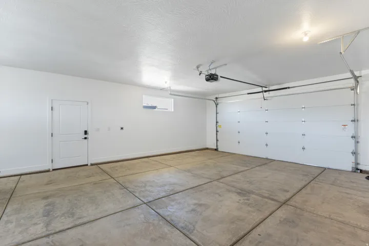 Concrete flooring with expansion joints, overhead garage door with automatic opener, side entry door, and small window