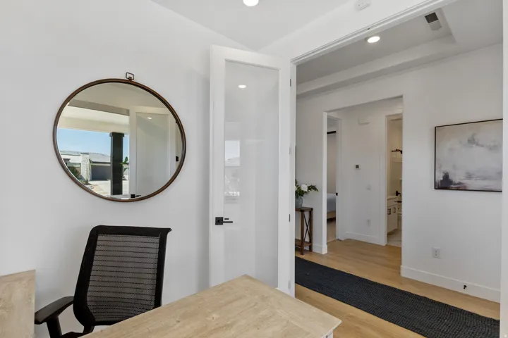 Recessed lighting, wood-finish flooring, white paneled walls, and a frosted glass-paneled door