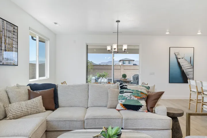 Spacious living area featuring light wood-finish flooring, recessed lighting, and a modern chandelier