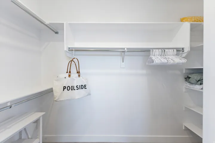 Built-in closet shelving system featuring multiple storage levels, an integrated hanging rod, and white finishes