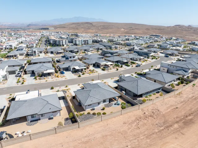 Expansive neighborhood featuring single-story residences with concrete tile roofs, paved streets, and desert landscaping