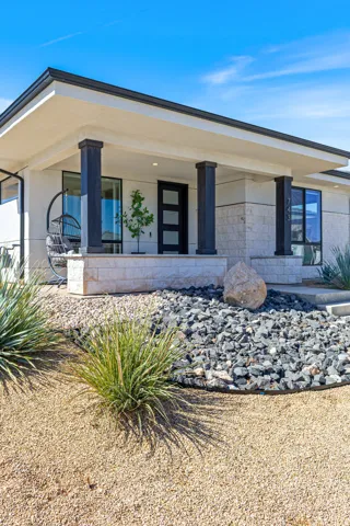 Contemporary exterior featuring a covered entry, stone veneer accents, and a modern dark-paneled door with frosted glass inserts