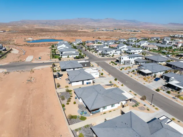 Residential street with a variety of single-story and multi-story homes, featuring gray roofs and light-colored exteriors