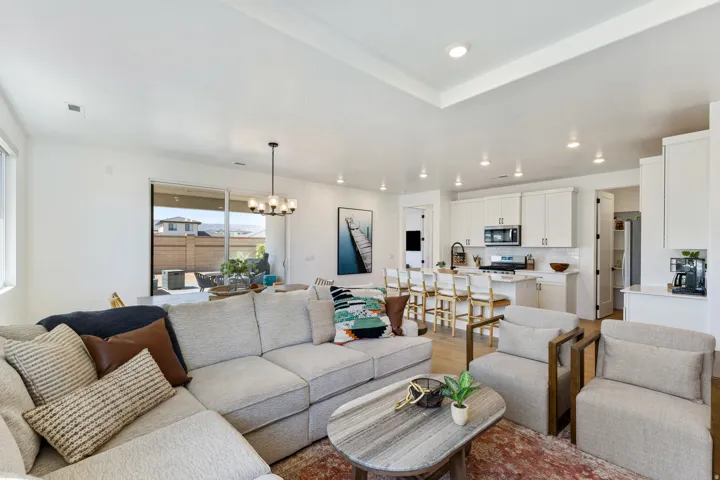 Open-concept living area featuring wood-finish flooring, white cabinetry, recessed lighting, and a tray ceiling