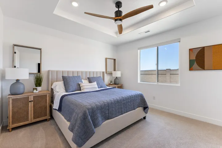 Recessed lighting in a ceiling tray, wood-finish ceiling fan, broad window, and light-toned carpet