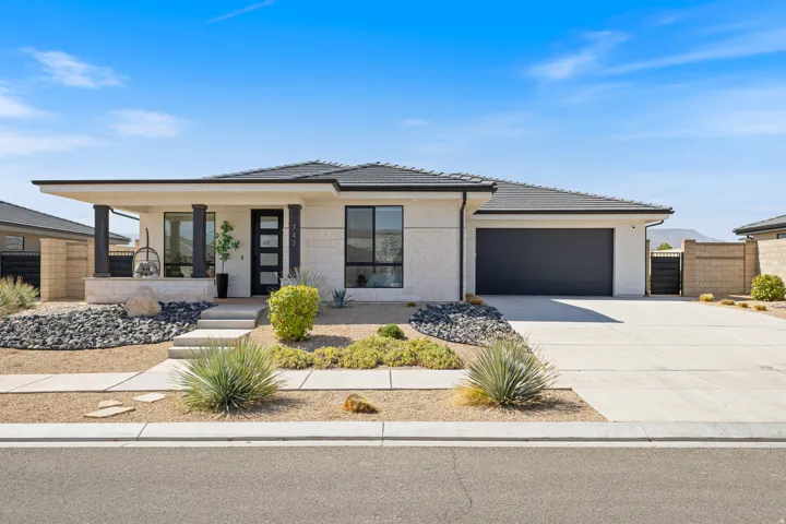 Contemporary exterior with a dark-tiled roof, white stone facade, and xeriscaped front yard