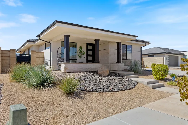 Modern exterior with a covered entry, decorative stone accents, and a xeriscaped front yard