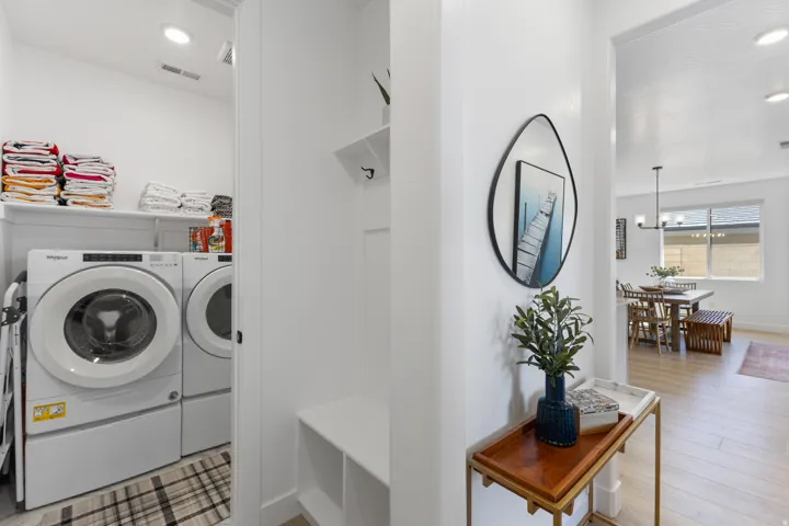 Dedicated laundry area featuring stacked appliances and open shelving