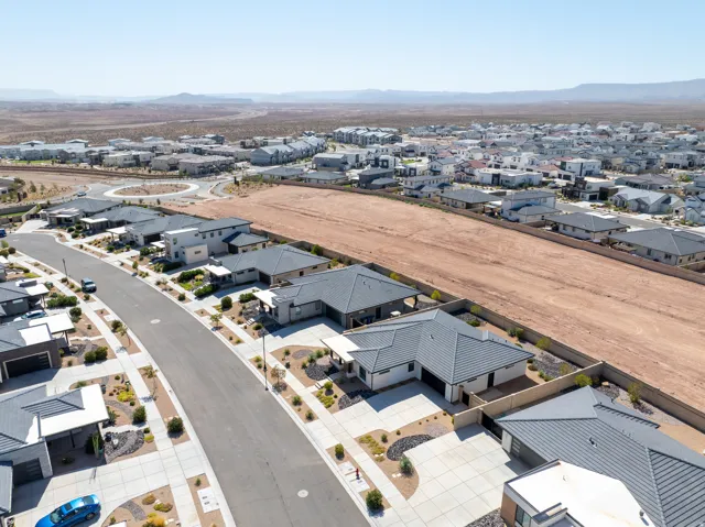 Residential street featuring modern homes with tile roofs, desert landscaping, and concrete driveways
