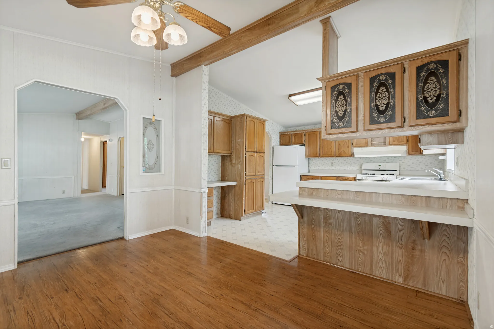 Wood-finish flooring, wood-beamed ceiling, built-in cabinetry, and a kitchen pass-through with countertop.