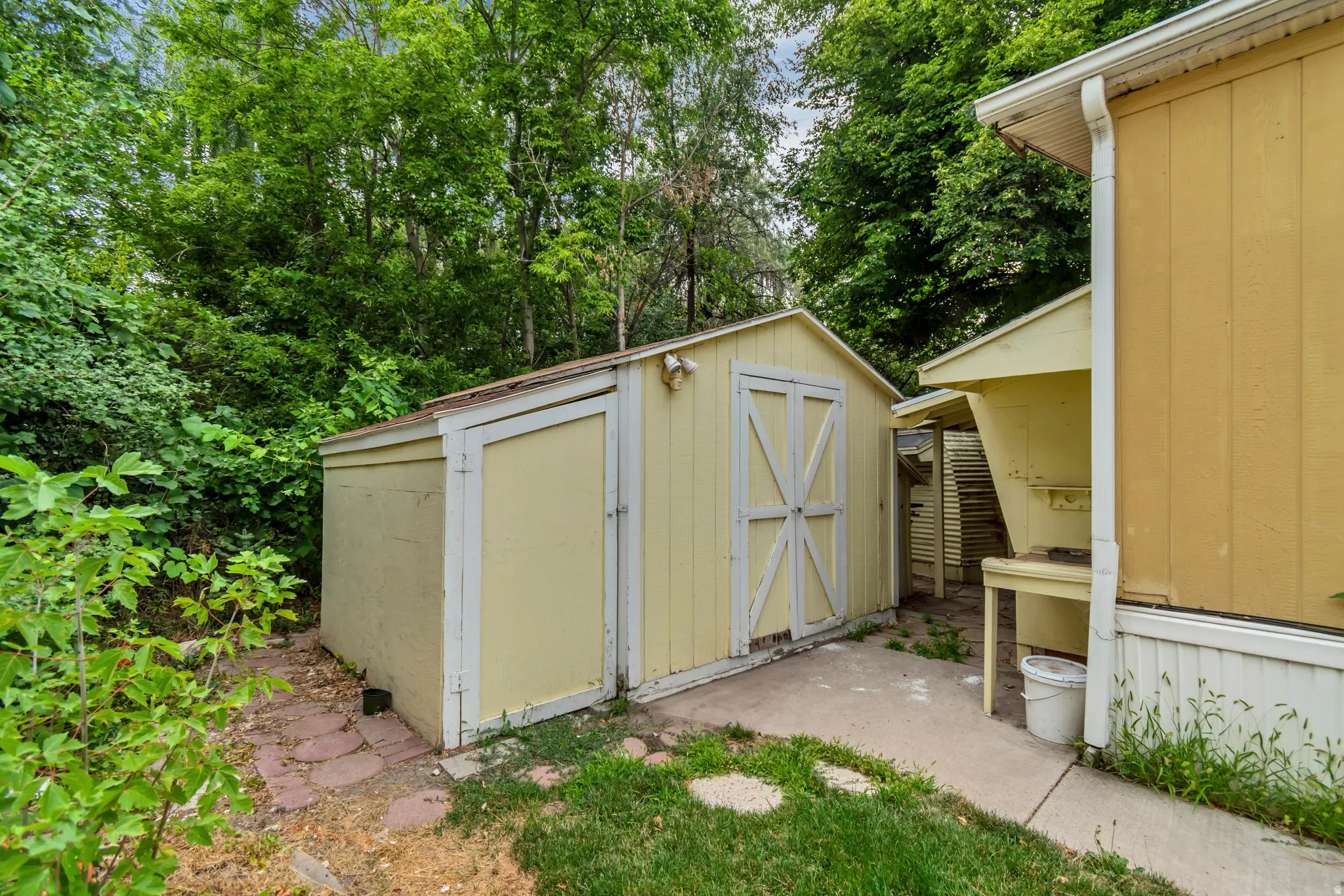Detached storage shed with double doors and workbench attached to back of home.