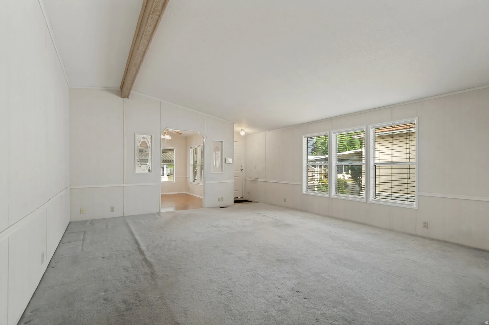Spacious family room featuring multiple windows, a vaulted ceiling with an exposed beam.