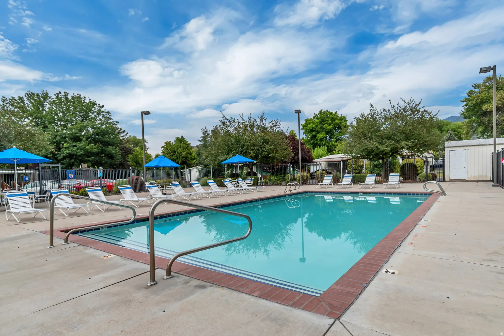 Rectangular swimming pool with integrated steps, surrounded by a concrete deck with brick coping