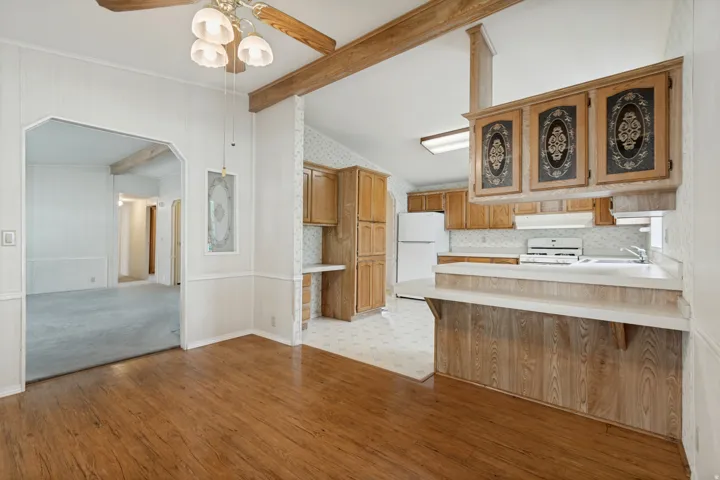 Wood-finish flooring, wood-beamed ceiling, built-in cabinetry, and a kitchen pass-through with countertop.