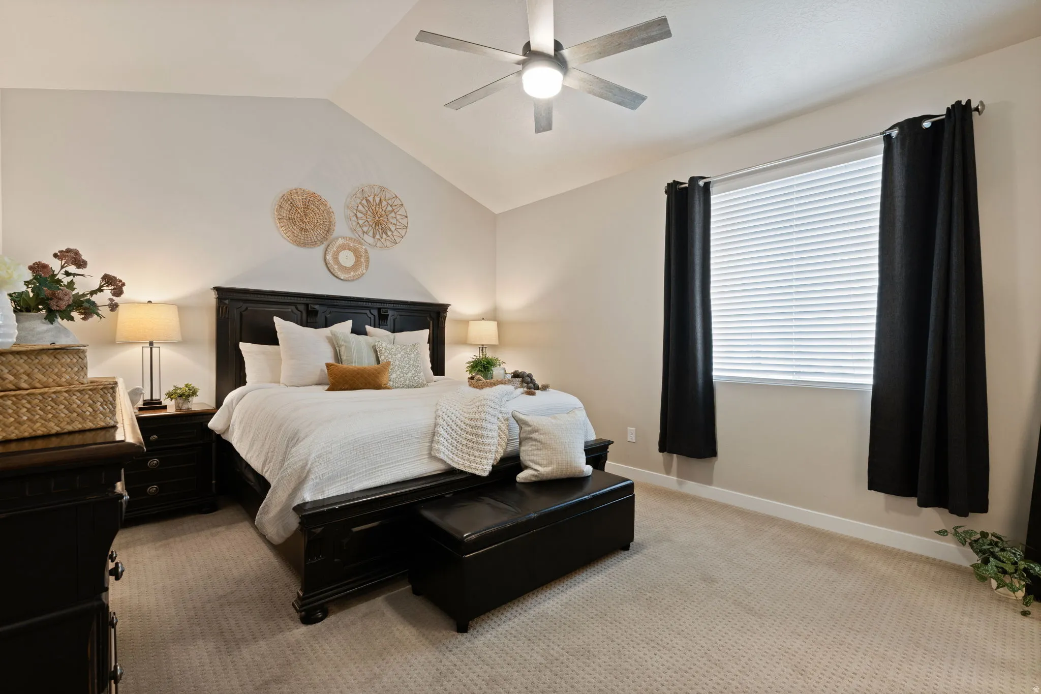 Vaulted ceiling featuring a ceiling fan with integrated lighting, window with blinds and dark drapery, and neutral-toned carpeting